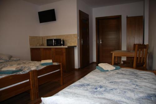 a bedroom with two beds and a table with a microwave at Miętusia Przystań - Wynajem Pokoi in Ciche