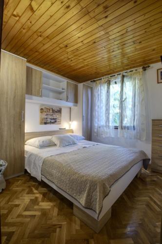 a bedroom with a large bed with a wooden ceiling at Apartman Tina in Grižane