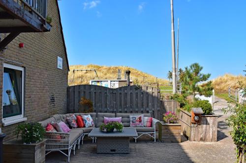 a patio with a couch and tables and a fence at Hotel Dichtbijzee in Oosterend