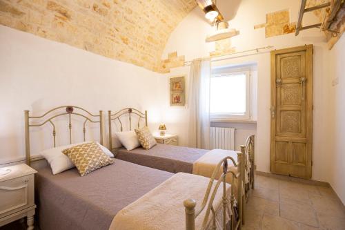 a bedroom with two beds and a window at Trullo Arteanima in Locorotondo