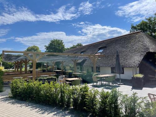 a patio with tables and chairs and a building at Luxe All season Chalet De Goudenregen in Balkbrug