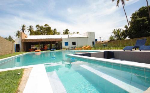 - une piscine d'eau bleue en face d'une maison dans l'établissement Tapiri Pousada - Rota Ecológica dos Milagres, à São Miguel dos Milagres