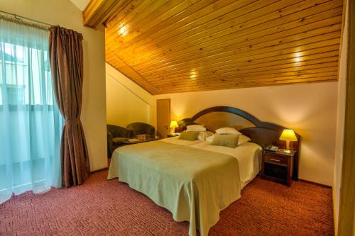 a bedroom with a large bed with a wooden ceiling at Hotel Ambient in Braşov