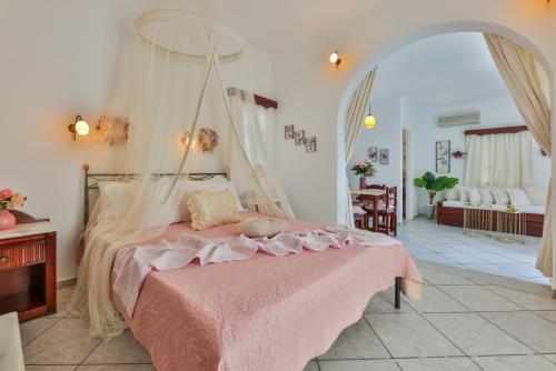1 dormitorio con cama con dosel y manta rosa en Sunrock Suites en Stelida