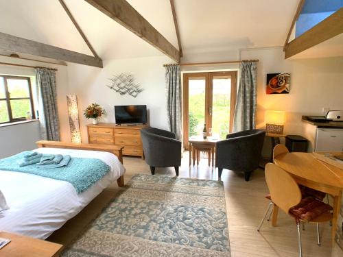 a bedroom with a bed and a dining room with a table at A Delightful Barn in a Peaceful and Private Setting, Close to Dartmoor and the Beautiful Tamar Valley in Gunnislake