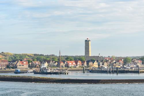 a river with a lighthouse in the background of a town at Hotel Dichtbijzee in Oosterend