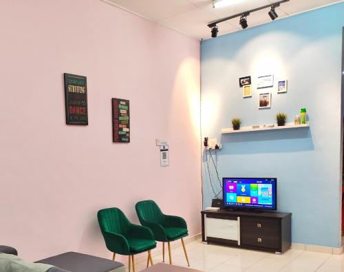 a waiting room with two green chairs and a tv at Kampar Sakura 2 Landed in Kampar