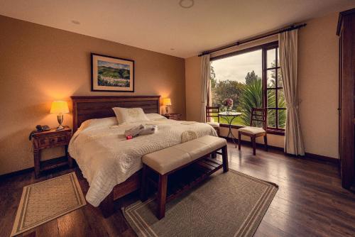 - une chambre avec un grand lit et une grande fenêtre dans l'établissement Hotel Hacienda Abraspungo, à Riobamba