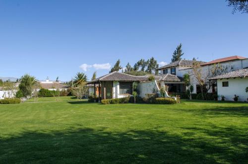 a house with a large yard with green grass at Hotel Hacienda Abraspungo in Riobamba