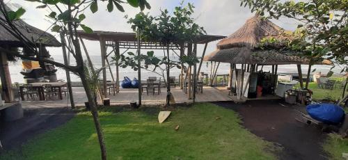 a pavilion with a table and chairs next to the ocean at Keramas Surf Hostel in Keramas