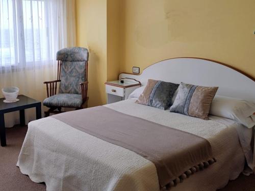ein Schlafzimmer mit einem großen Bett und einem Stuhl in der Unterkunft Hostal J.B in Malpica