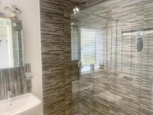 y baño con ducha acristalada, aseo y lavamanos. en 2 Bedroom cottage sleeps 4 with Hot-tub, & shared Pool use, en Sennen