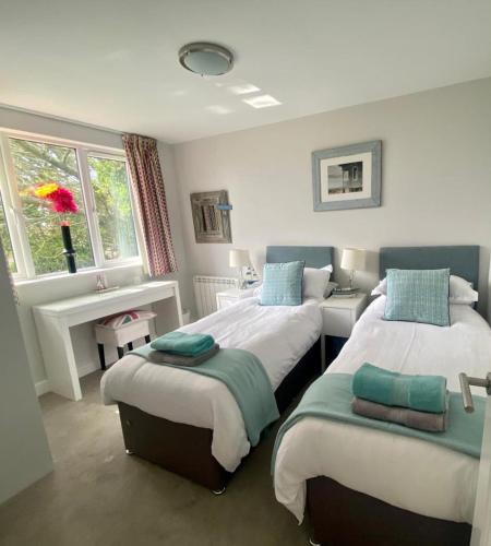 a bedroom with two beds and a window at 2 Bedroom cottage sleeps 4 with Hot-tub, & shared Pool use in Sennen