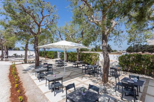 um pátio exterior com mesas, cadeiras e um guarda-sol em B&B Villa Massimo em Porto Cesareo