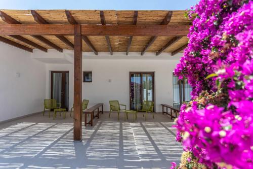 a patio with tables and chairs and purple flowers at B&B Villa Massimo in Porto Cesareo