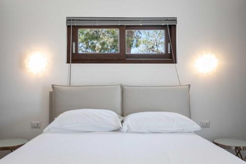 a white bed with two pillows and a window at B&B Villa Massimo in Porto Cesareo