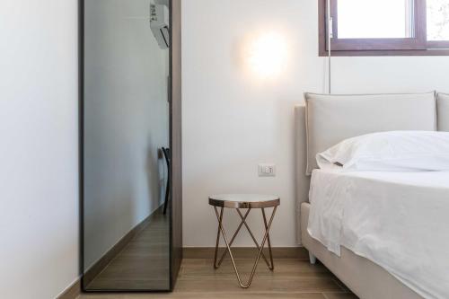 a bedroom with a bed and a stool next to a mirror at B&B Villa Massimo in Porto Cesareo