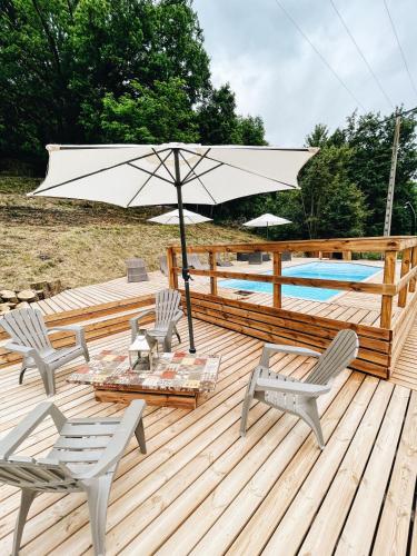 une terrasse en bois avec deux chaises et un parasol dans l'établissement chalet des Illes HOKKAIDO IIIIII, à Prat-et-Bonrepaux