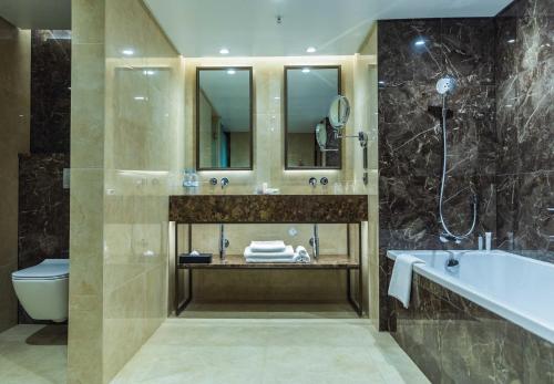a bathroom with a tub and a toilet and a sink at InterContinental Lusaka, an IHG Hotel in Lusaka