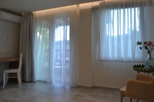 a living room with white curtains and a table and a chair at Liadromia Hotel in Patitiri