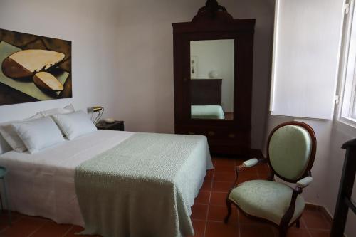 a bedroom with a bed and a chair and a mirror at TI8-Travessa das Invernas 8 in Évora