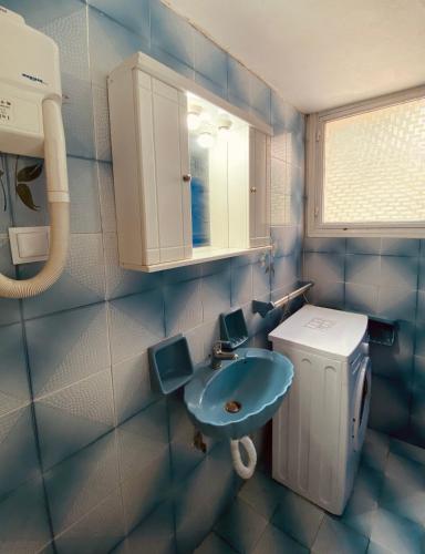 a blue bathroom with a sink and a mirror at Beach House in Lefkimmi