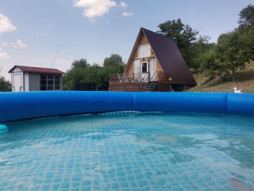 a large swimming pool with a house in the background at Cabana Samira 1 in Tăşnad