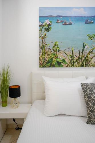 a bedroom with a white bed with a painting on the wall at Daniel's garden apartment in Eilat