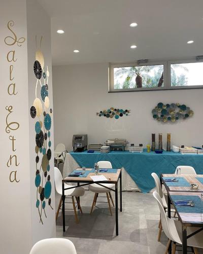 a dining room with tables and chairs and a blue counter at Hotel Portum in Giardini Naxos