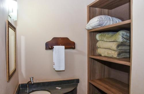 a bathroom with a sink and a shelf with towels at Hotel Fazenda Haras in Olímpia