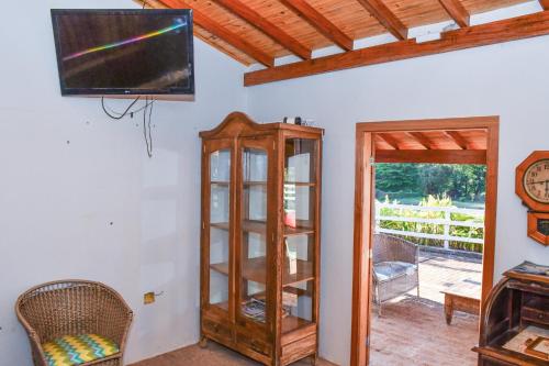a living room with a tv and a wooden cabinet at Hotel Fazenda Haras in Olímpia