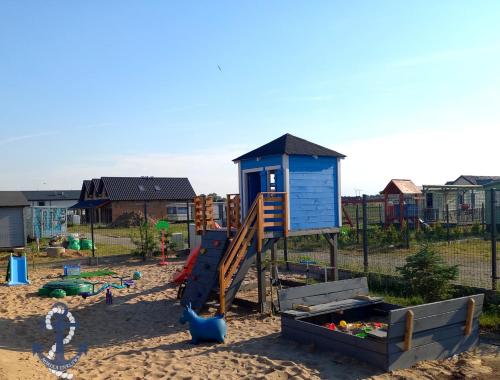 um parque infantil com escorrega na areia em Morska Enklawa em Gąski