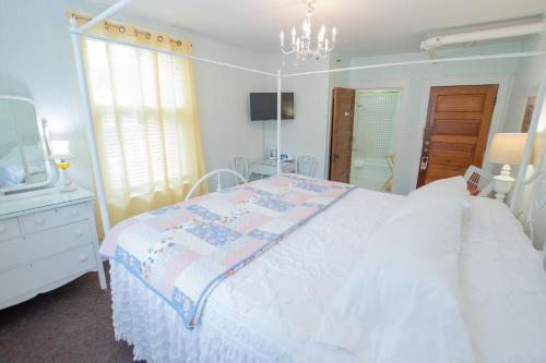 a bedroom with a white bed and a chandelier at Terrace Inn and 1911 Restaurant in Petoskey
