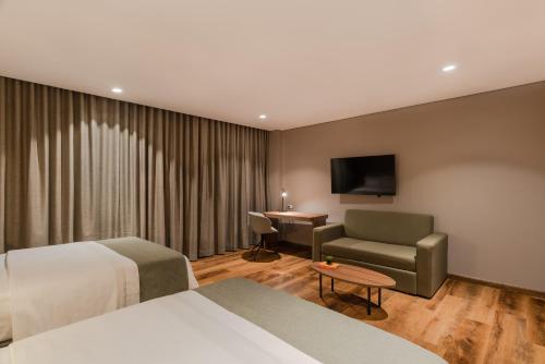 a hotel room with a bed and a chair and a desk at Hotel Sites Barranquilla in Barranquilla