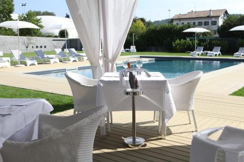 un tavolo e sedie su una terrazza accanto alla piscina di Hotel Franz a Gradisca dʼIsonzo