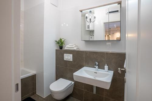 a bathroom with a sink and a toilet and a mirror at Morska vila 6 Luxury Apartment Žnjan in Split