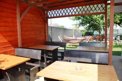 eine Terrasse mit Tischen, Bänken und einer Hängematte in der Unterkunft Vila Aty & Michelle in Vama Veche