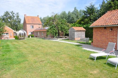 a yard with two chairs and a brick building at B&B Pierre-Marie in Bovekerke
