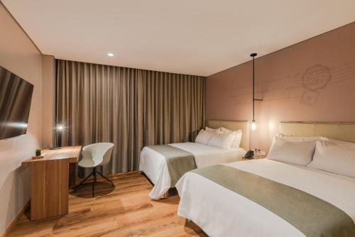 a hotel room with two beds and a desk at Hotel Sites Barranquilla in Barranquilla