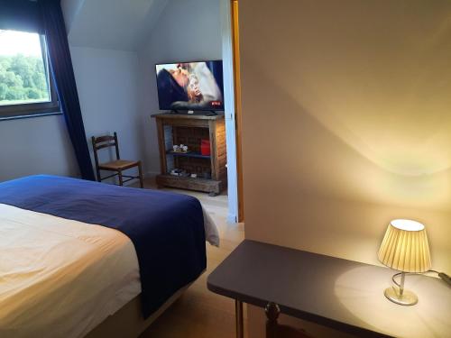 a bedroom with a bed and a tv and a table at B&B Scheldekant in Oudenaarde