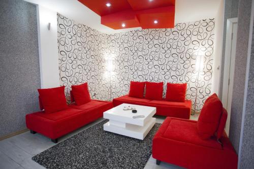 ein Wohnzimmer mit roten Sofas und einem weißen Tisch in der Unterkunft Apartment Red in Belgrad