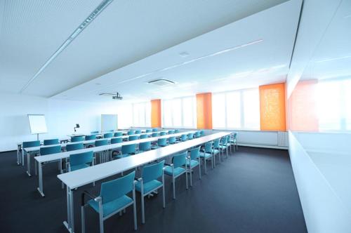 an empty lecture room with tables and blue chairs at Sankt Magdalena in Linz