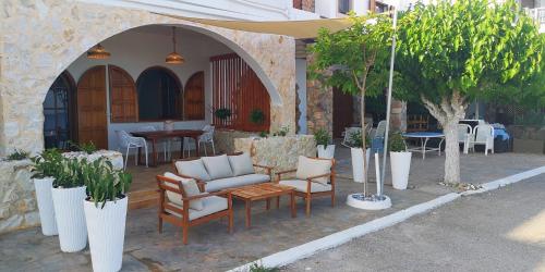 een patio met stoelen, tafels en bomen bij Relax Seaside House in Charaki