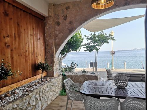 a patio with a table and chairs and the ocean at Relax Seaside House by living in blue in Haraki