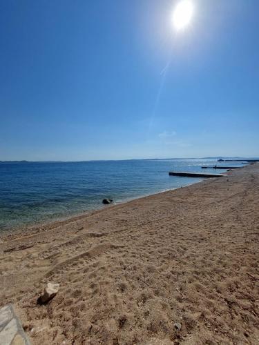 a sandy beach with the ocean on a sunny day at Apartment by the sea Renata in Punta Skala in Petrcane