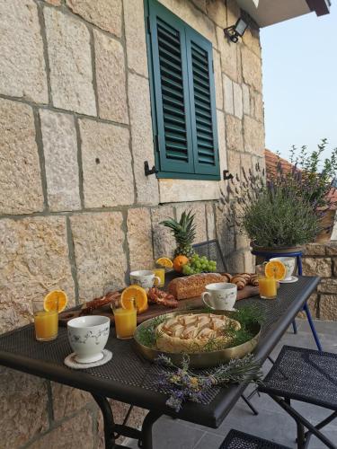 a table with a plate of food and oranges on it at Apartmani Tripalo in Imotski