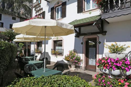 a patio with tables and umbrellas in front of a building at Hotel Stella Alpina in Fai della Paganella