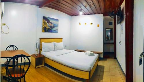 um quarto com uma cama, uma mesa e uma cadeira em Marion Hotel em Manila