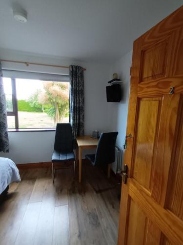 a bedroom with a desk and chairs and a window at Arley House B & B in Dundrum
