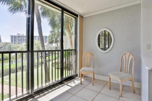 two chairs on a balcony with a view of palm trees at Midnight Cove II 823 in Siesta Key